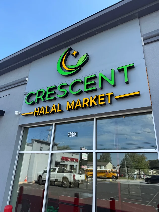 Close-up of the green and gold Crescent Halal Market sign above the entrance